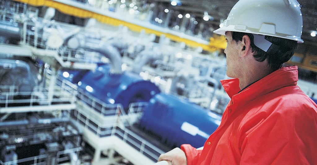 Engineer wearing hard hat overlooking the interior of a Nuclear power station