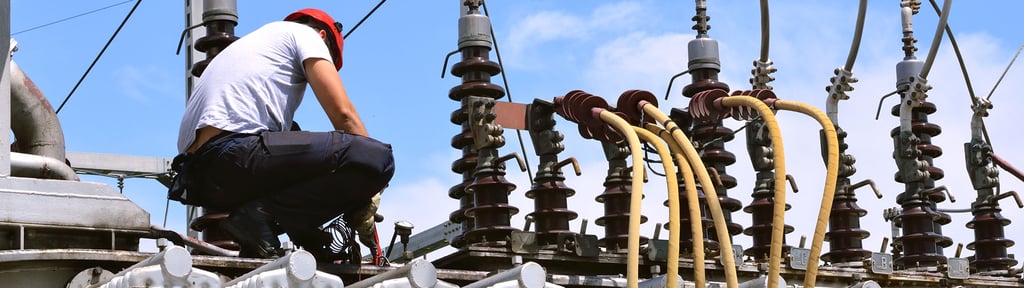 Electrician working on high voltage transformer in power station