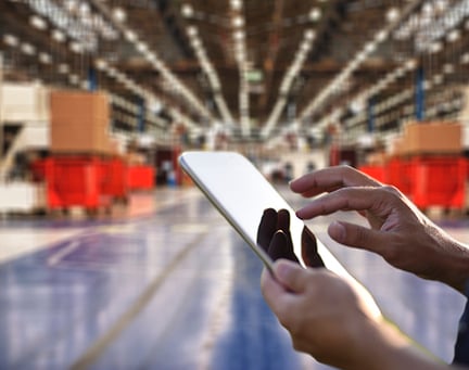 Person using a tablet with a warehouse in the background