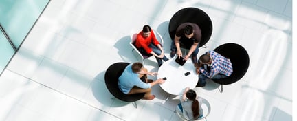 Birds eye image of a group of people conducting a meeting sitting down around a table